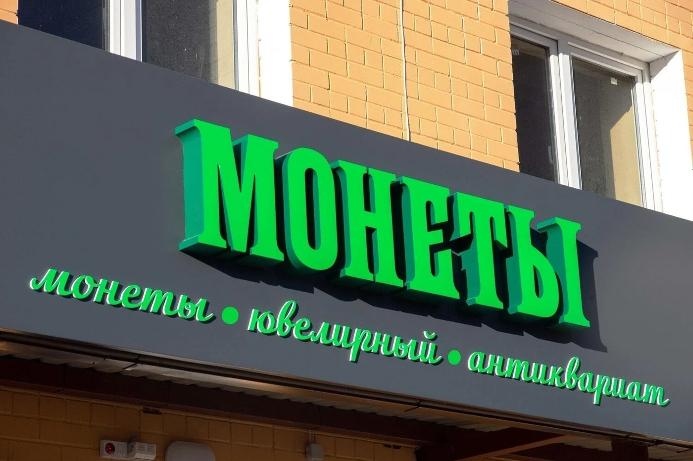 Зелёные объёмные буквы МОНЕТЫ над входом в магазин