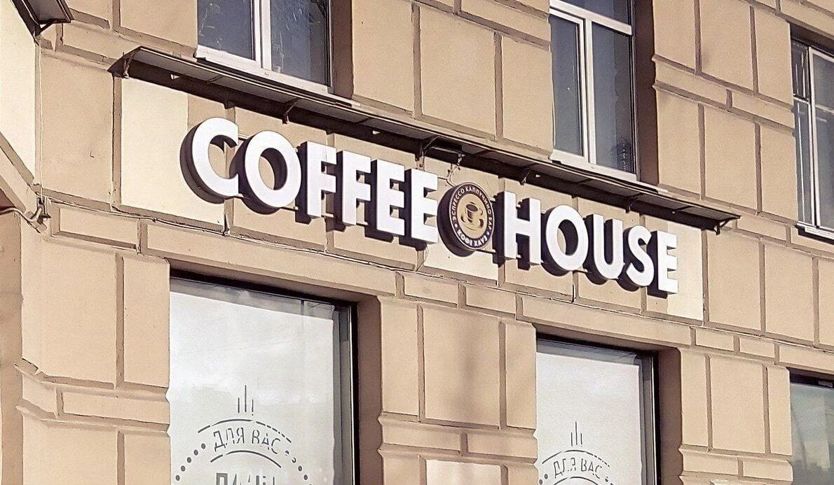 Белые объёмные буквы COFFEE HOUSE на тёмном основании над входом
