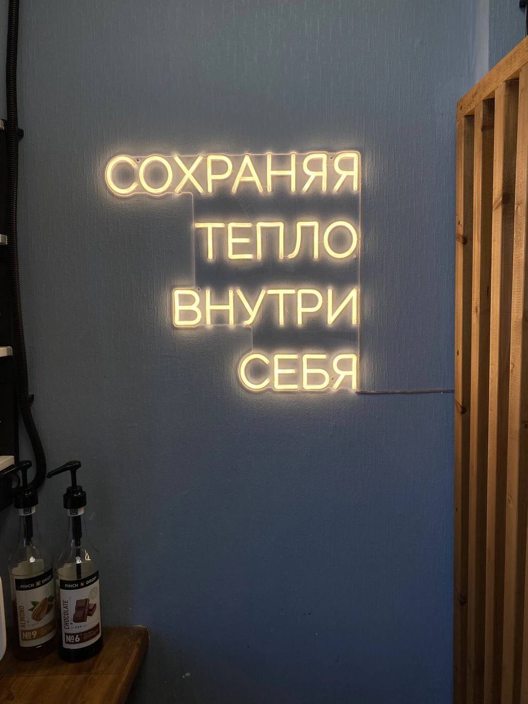 Тёплая неоновая надпись СОХРАНЯЯ ТЕПЛО ВНУТРИ СЕБЯ в интерьере
